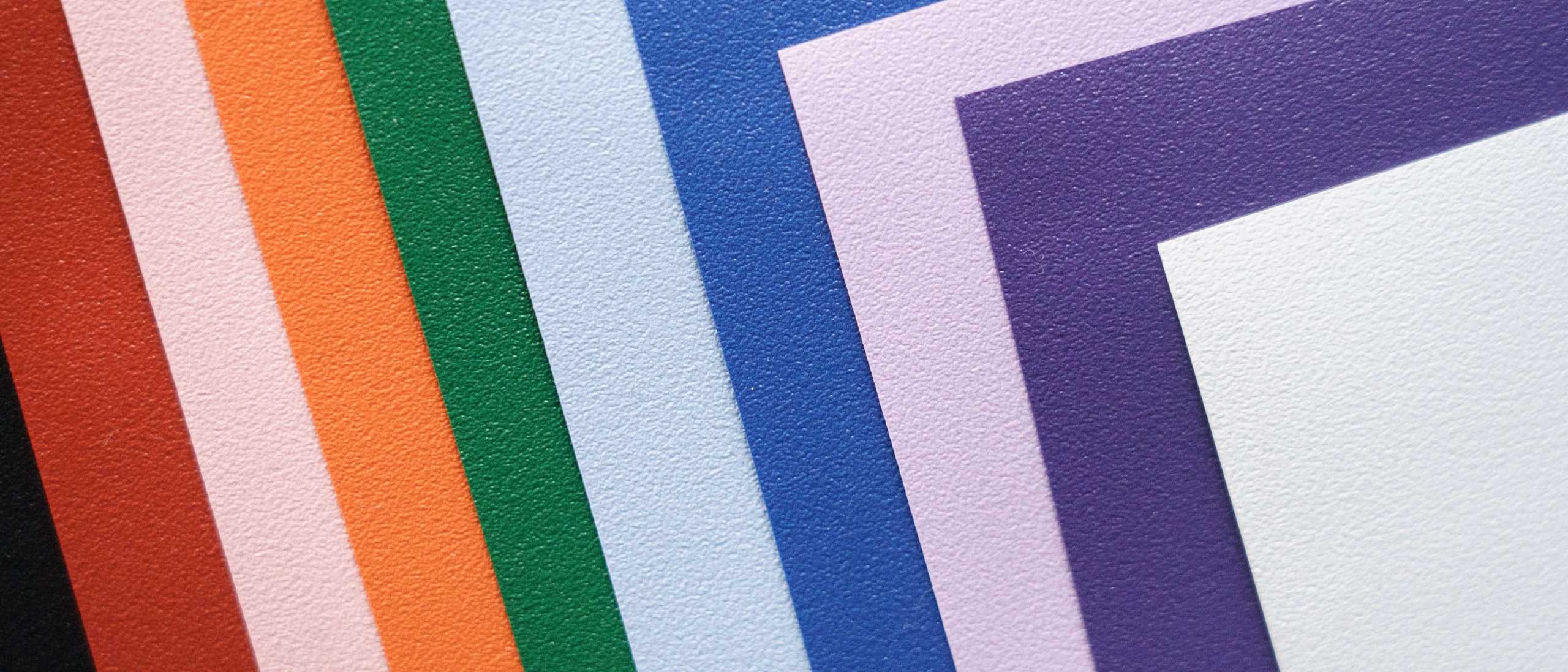 Guardian sleeves fanned into a corner of stacked color bands, black through white